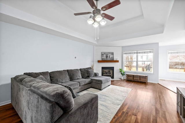 living room with hardwood / wood-style floors, a tray ceiling, and ceiling fan