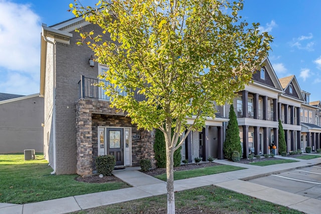 view of front of house featuring a front lawn, a balcony, and cooling unit