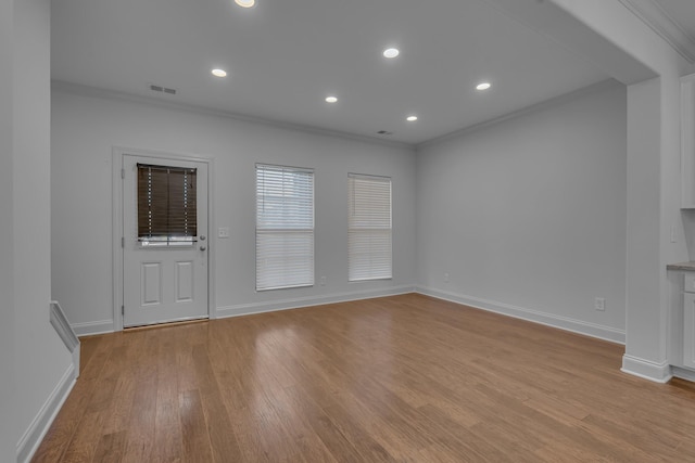 unfurnished living room featuring light wood-type flooring and ornamental molding