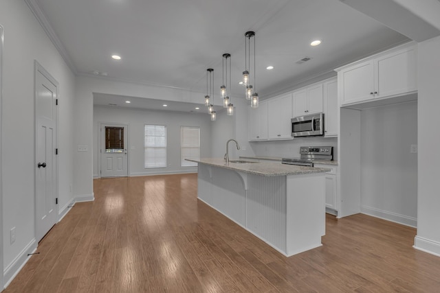 kitchen featuring white cabinetry, an island with sink, decorative light fixtures, and appliances with stainless steel finishes