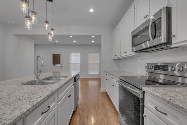 kitchen featuring light stone countertops, backsplash, stainless steel appliances, sink, and white cabinets