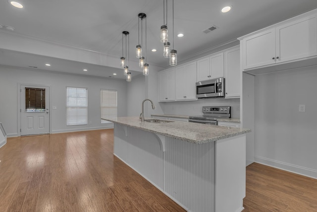 kitchen featuring appliances with stainless steel finishes, sink, decorative light fixtures, a center island with sink, and white cabinets