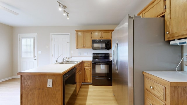 kitchen with sink, light hardwood / wood-style floors, a kitchen island, and black appliances