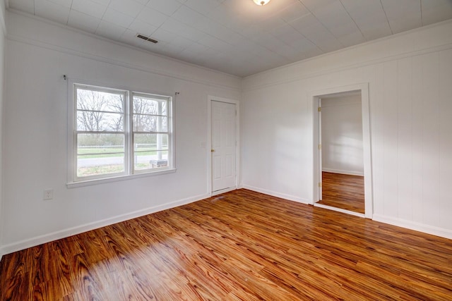 empty room with hardwood / wood-style flooring and crown molding