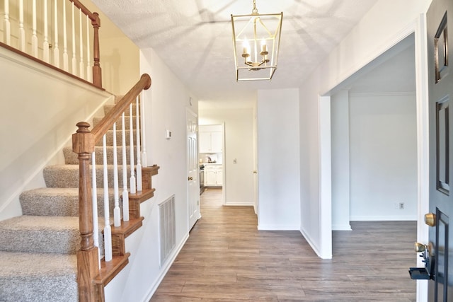 foyer with wood-type flooring, a textured ceiling, and a chandelier