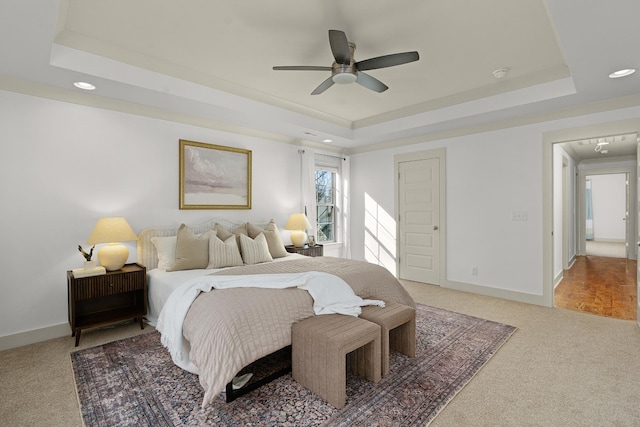 bedroom featuring carpet floors, a raised ceiling, and ceiling fan