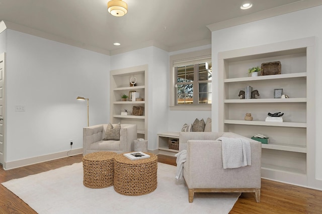 sitting room with wood-type flooring and built in features