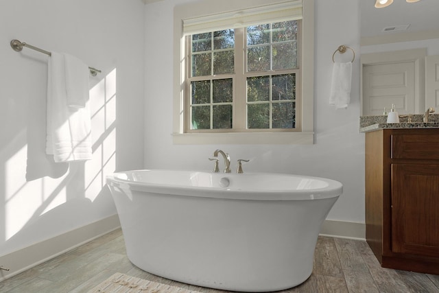 bathroom with a tub, hardwood / wood-style floors, and vanity