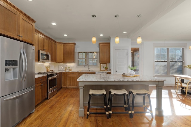 kitchen with a center island, sink, decorative light fixtures, a kitchen bar, and stainless steel appliances