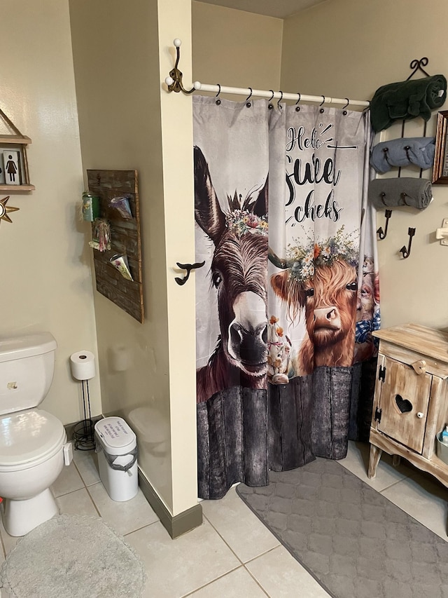 bathroom featuring toilet, tile patterned flooring, and baseboards