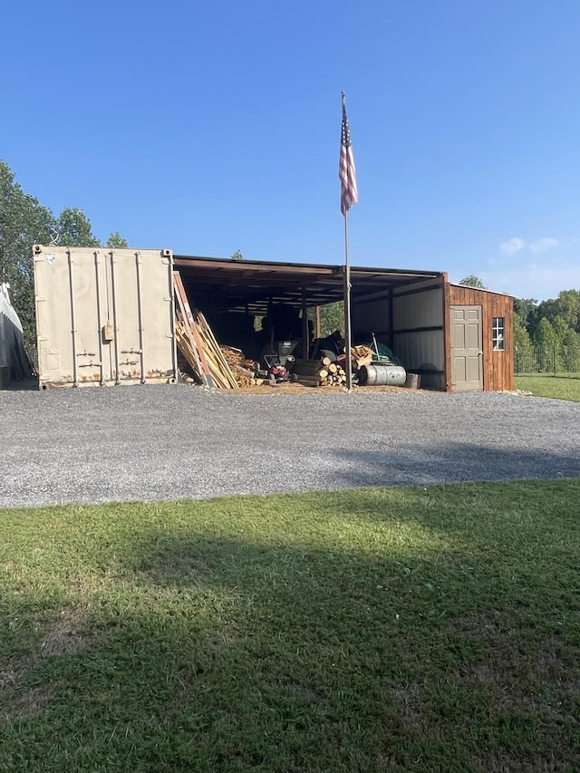 view of outbuilding featuring a carport, an outbuilding, and gravel driveway