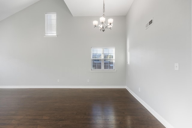 spare room featuring an inviting chandelier, plenty of natural light, and dark wood-type flooring