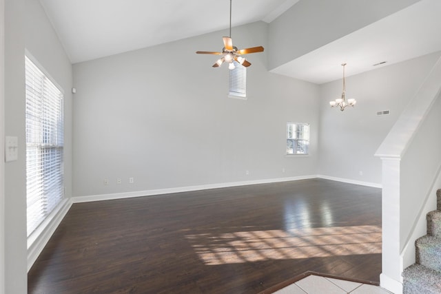 unfurnished living room with a wealth of natural light, dark hardwood / wood-style flooring, and ceiling fan with notable chandelier