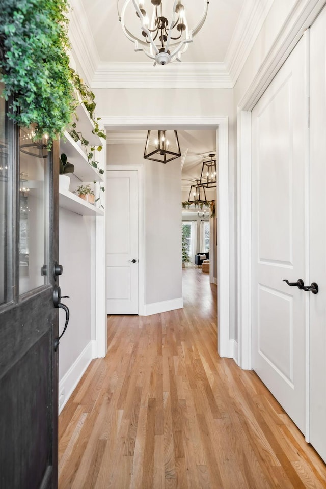 hallway featuring light hardwood / wood-style floors, crown molding, and an inviting chandelier