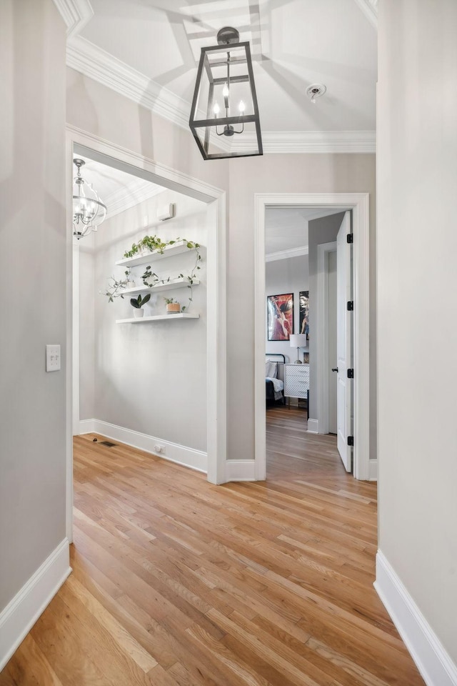 corridor with hardwood / wood-style flooring, ornamental molding, and a chandelier