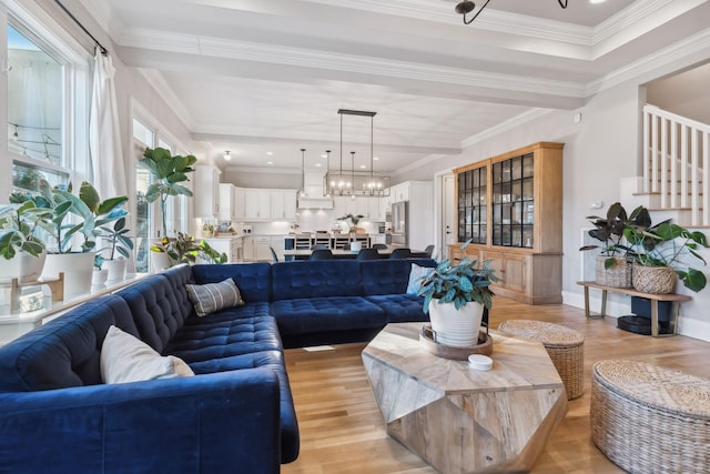 living room with an inviting chandelier, ornamental molding, and light wood-type flooring