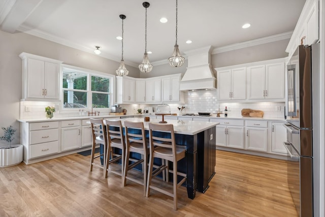 kitchen featuring appliances with stainless steel finishes, a kitchen breakfast bar, custom range hood, a center island, and white cabinetry