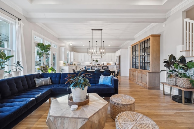 living room featuring a chandelier, light wood-type flooring, and crown molding