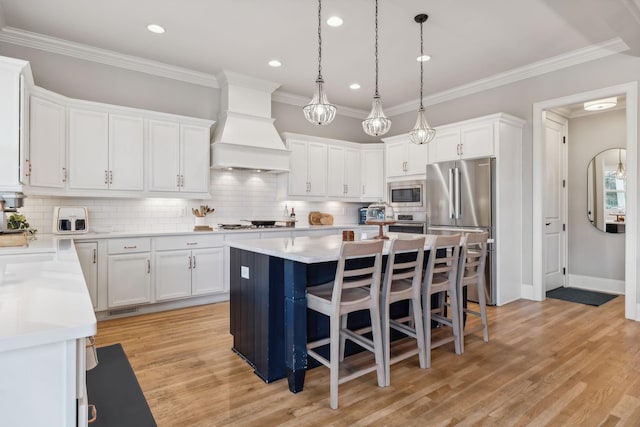 kitchen with white cabinets, stainless steel appliances, a kitchen island, and premium range hood