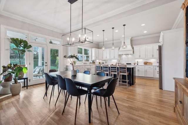 dining area with a chandelier, crown molding, french doors, and light hardwood / wood-style floors