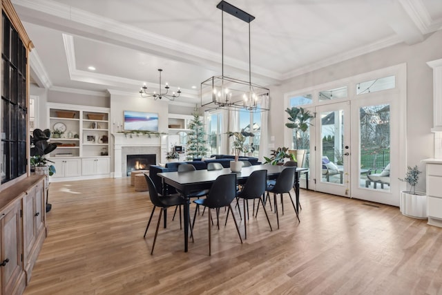 dining space with french doors, light hardwood / wood-style floors, an inviting chandelier, and crown molding