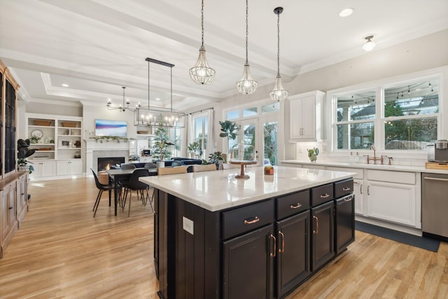 kitchen featuring white cabinets, pendant lighting, a kitchen island, and stainless steel dishwasher