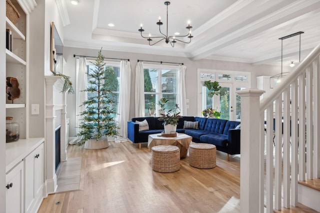 living room with a notable chandelier, crown molding, a tray ceiling, and light hardwood / wood-style flooring