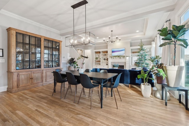 dining room featuring light wood-type flooring, ornamental molding, and a notable chandelier