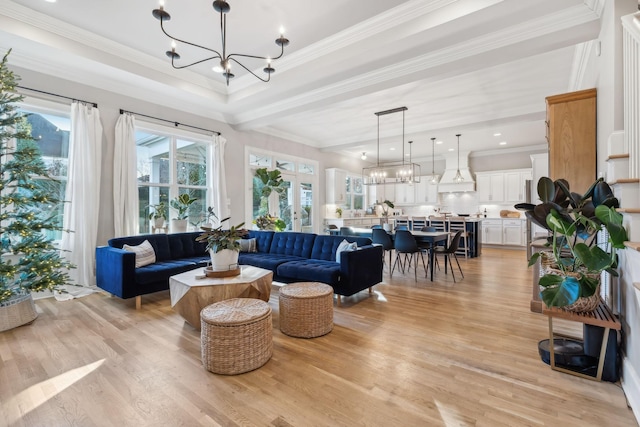 living room featuring crown molding, plenty of natural light, light hardwood / wood-style floors, and an inviting chandelier