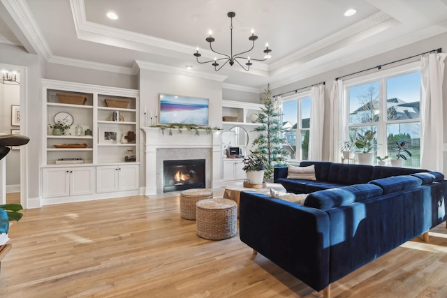 living room with a chandelier, light wood-type flooring, and a tray ceiling