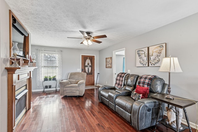 living room with dark hardwood / wood-style floors, ceiling fan, a textured ceiling, and a tile fireplace