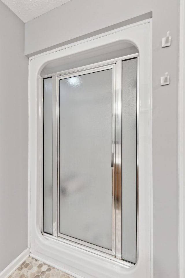 bathroom featuring an enclosed shower and a textured ceiling