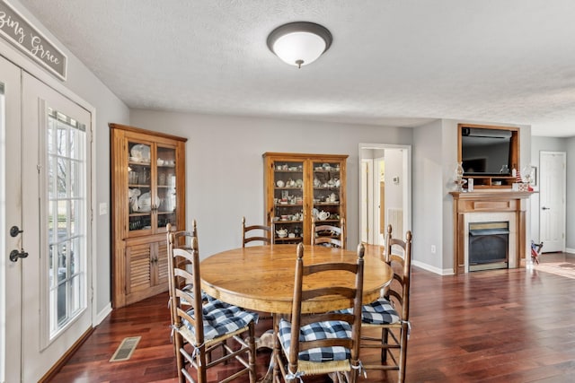 dining room with dark hardwood / wood-style floors, a textured ceiling, and french doors