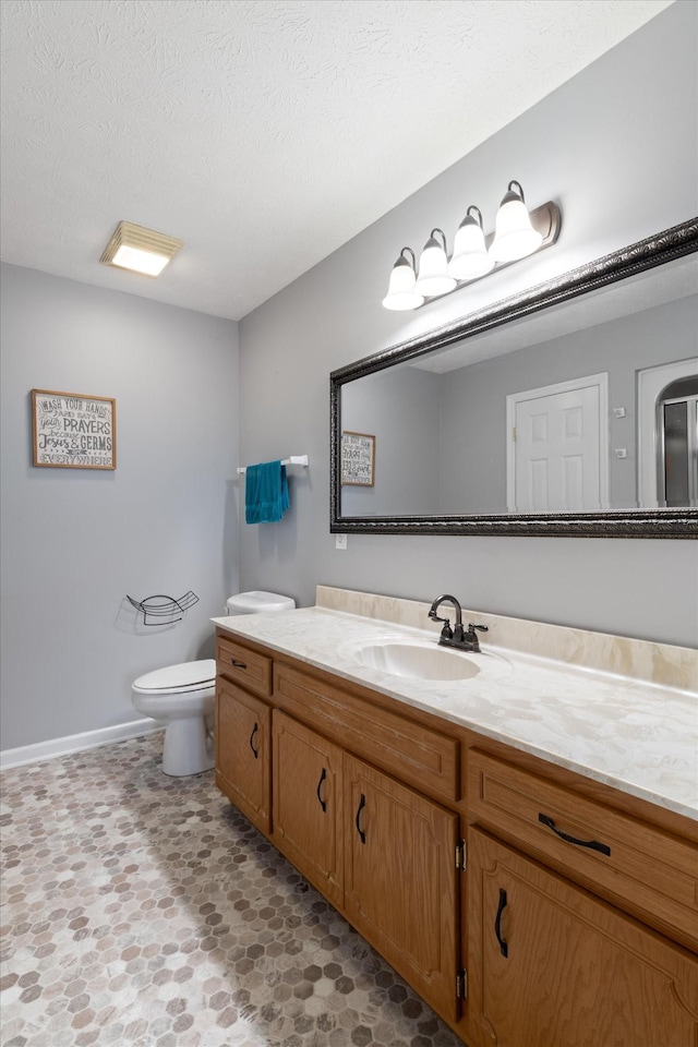 bathroom featuring vanity, a textured ceiling, and toilet