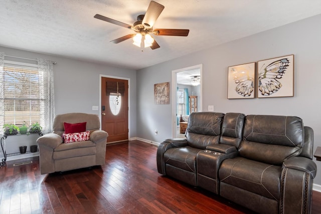 living room featuring dark wood-type flooring, ceiling fan, and plenty of natural light