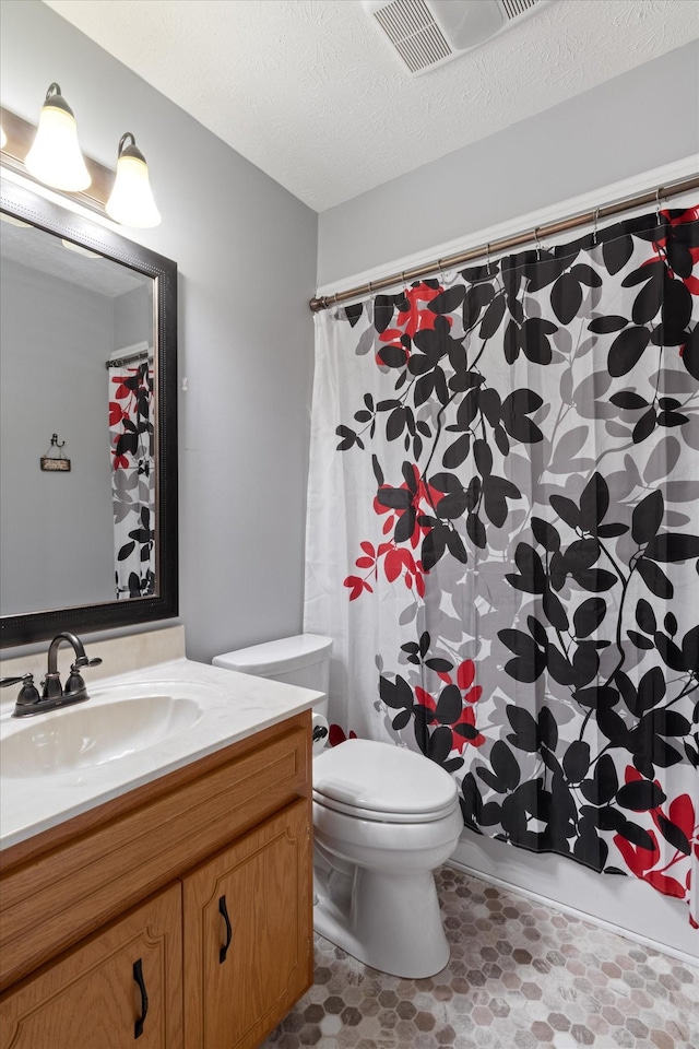 bathroom with vanity, toilet, and a textured ceiling