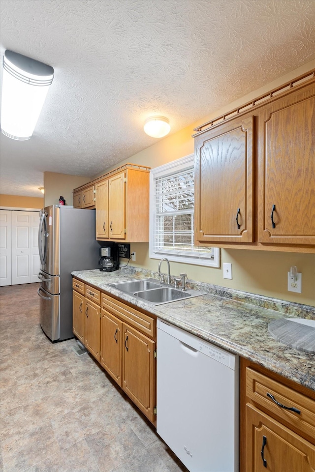 kitchen with stainless steel fridge, sink, a textured ceiling, and white dishwasher