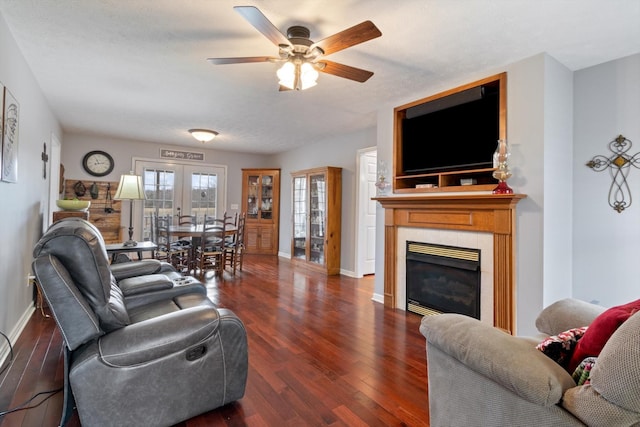 living room featuring a tiled fireplace, dark wood-type flooring, french doors, and ceiling fan