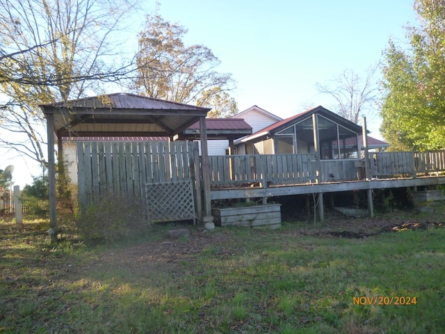 rear view of house with a lawn, a wooden deck, a sunroom, and a gazebo