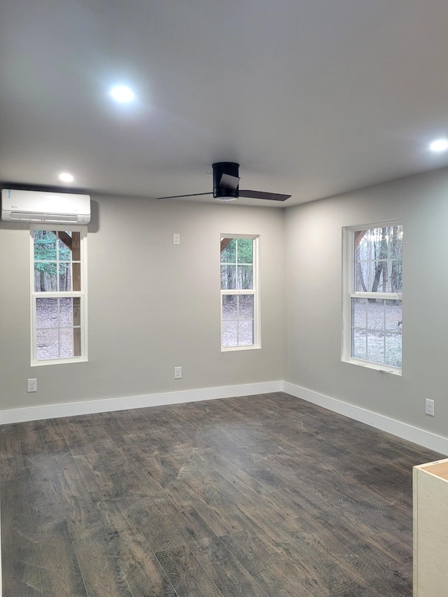 unfurnished room with a wealth of natural light, dark hardwood / wood-style floors, a wall mounted AC, and ceiling fan