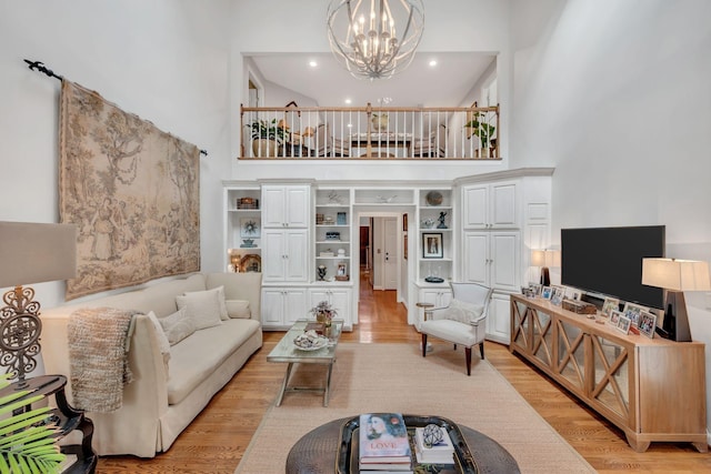 living area featuring a notable chandelier, light wood-style flooring, and a towering ceiling