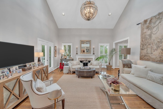 living room with a towering ceiling, light hardwood / wood-style floors, and an inviting chandelier