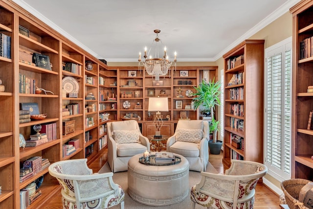 living area featuring bookshelves, crown molding, light wood finished floors, and an inviting chandelier