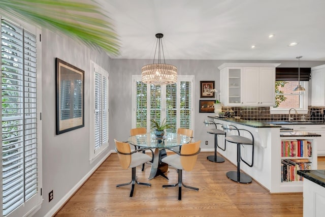 dining room with sink, plenty of natural light, a chandelier, and light wood-type flooring