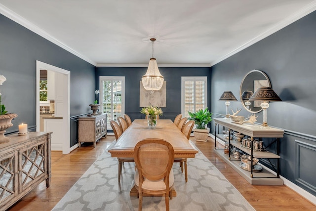 dining area featuring ornamental molding, light wood-type flooring, and a notable chandelier