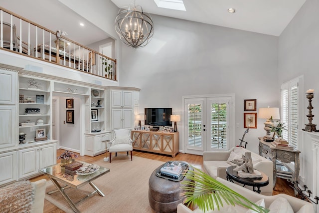 living room with a chandelier, a high ceiling, light hardwood / wood-style floors, and french doors