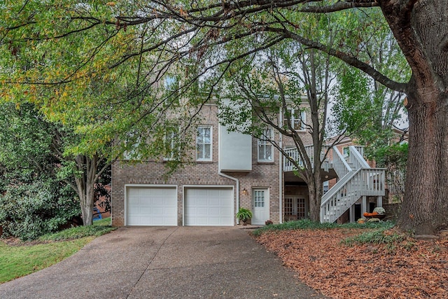 view of front of home featuring a garage, brick siding, driveway, and stairway