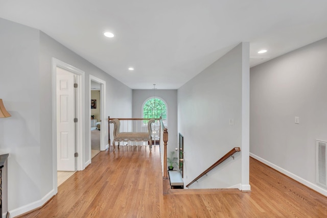 corridor with light wood-type flooring, baseboards, and an upstairs landing