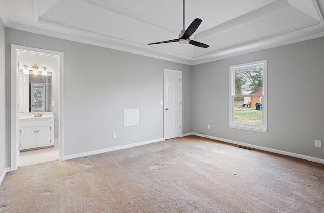 unfurnished room featuring light carpet, a tray ceiling, ceiling fan, and crown molding