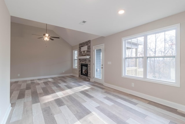 unfurnished living room with ceiling fan, a stone fireplace, light hardwood / wood-style flooring, and vaulted ceiling